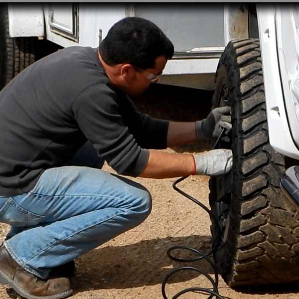 man inflating off road tire white truck